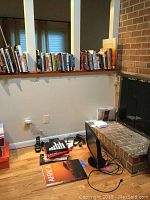 Books arranged along a wall shelf and floor near a fireplace, with some larger books on Africa visible on the floor below