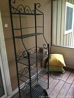 Full view of taller metal rack with five shelves and decorative scrollwork, showing open metal slats and aged condition with rust and soiling.