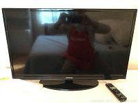 Front view of Samsung 32-inch HDTV with black bezel and stand, remote on side.
