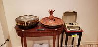 Full view of all three items: wooden lazy susan on table, baseball clock on lazy susan, and Socialite Olympia typewriter on adjacent stand.
