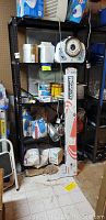 Black metal shelving unit with four metal shelves, organized with various storage items not included in the sale.