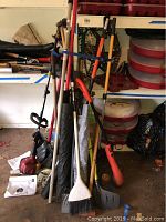 Full view of yard tool collection including gas trimmer, shovels, broom, rake, and edged attachment