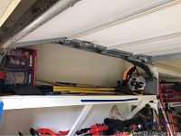 Shelf with Ryobi yellow handled blower, post hole digger, and other tools visible.