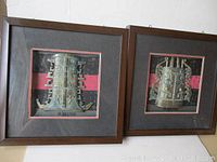 Two shadow box frames displayed side by side, each with a half Chinese temple bell mounted inside on black and red background, showing full arrangement and framing.