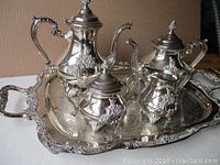 Full view of coffee pot, teapot, cream and sugar pots arranged on large ornate silverplate tray showing overall design and condition.