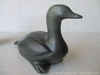 Front view of grey stone bird carving showing polished surface and form