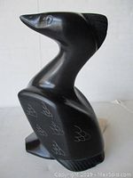 Front right angled view of bird carving showing incised feather details and smooth polished black stone material.