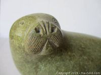 Close-up of walrus carving head showing carved whiskers and incised eyes.