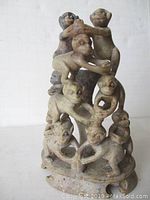 Front and side view of the vintage Chinese stone carving depicting monkeys in a pyramid formation.