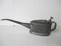 Side view of the vintage railway oil can showing the long curved spout, handle, and push bottom.