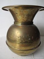 Front view of brass spittoon showing the embossed Union Pacific steam locomotive logo and the shape of the flared top and rounded body.