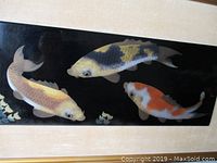 Close-up of three koi fish in high relief on black background showing gold highlights and detail.