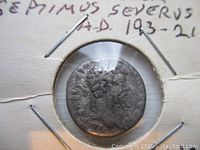 Front side of silver coin showing profile bust of Emperor Septimius Severus with laurel wreath.
