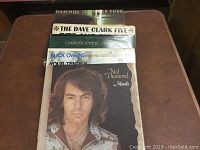 25 assorted vinyl records stacked vertically, visible artists include Neil Diamond, Buck Owens, Christopher Cross, The Dave Clark Five and Dan Hill