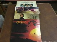 Photo showing a stack of vinyl records with visible front covers, including Air Supply, Olivia Newton-John, Glen Campbell, and John Paul and Mary.