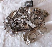 Top view of sterling silver scrap lot showing mix of chains, flat pieces, and small items.