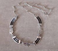 Full view of the bracelet laid flat, showing 4 elephant silver links alternating with 4 black enameled curved segments.
