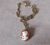 Front view of gold filled shell cameo pendant on brass chain showing detailed carved profile.