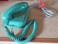 Photo of the vintage aqua green push button phone showing the entire phone along with coiled and two additional cords.