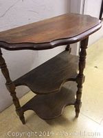 Side view of wooden 3-tier D-shaped shelf table showing scalloped edges and turned spindle legs.