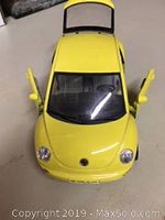 Yellow Volkswagen New Beetle diecast model car with open front hood and doors, showing detailed interior.