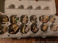 Photo showing all ceramic tea figurines arranged in a cardboard egg carton, depicting a nativity scene with various characters and animals.