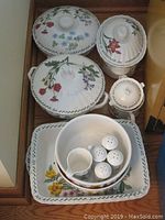 Image of three covered casseroles in different sizes, sugar bowl with lid, round serving bowl, and square serving platter with floral patterns and green vine accents.