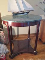 Full front view of the marble top round side table with wooden legs and green marble surface, showing table proportions and setting.