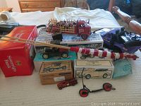 Overview of lot including Anheuser Busch Budweiser red truck loaded with barrels, collectible banks in boxes, red Sovereign Ballast box, small toys, and the metal striped chimney piece.