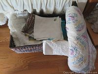 Basket with assorted linens, handkerchiefs, and aprons showing lace and embroidery