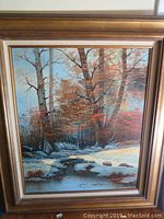 Full view of framed landscape painting with trees and stream in a 24x20 size.