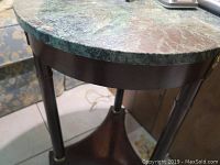 Close-up photo showing the green marble top and part of the polished wooden base, highlighting the marble texture.