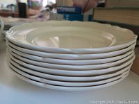 Stack of eight white Wedgwood Queen's Ware dinner plates showing scalloped edges and classic design.