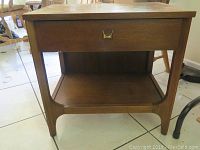 Front view of wooden side table with drawer and lower shelf.
