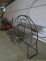 Photo showing metal wood racks and assortment of wood kindling pieces on floor in basement setting.