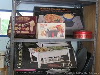 Electric warming tray, Gourmet Buffet warming tray with chafing fuel cans, Fryall deep fryer, and Wear-Ever Super Shooter cookie cutter set displayed on shelf.