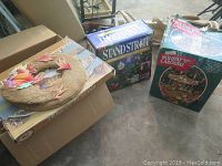 Photo of boxed Holiday Carousel, Holiday Living Christmas Tree Stand box, and decorative wreath with autumn leaves on cardboard boxes.