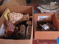 Box containing classical bust, wooden shoes, red bird figurine, and other small items