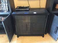 Black wooden cabinet with two doors, the left door is open and broken, showing details and condition of the cabinet.