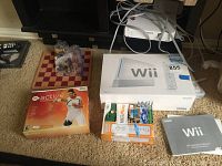 Photo showing Nintendo Wii console box, chess set, EA Active game case, Wii Play game, Wii Operation Manual, and controllers with cables.