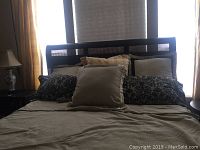 Front view of the king size bed made with beige comforter, pillows including solid beige and patterned cases, showing overall colors and style