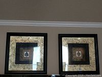 Pair of black framed wall art pictures with gold-toned textured mats and botanical leaf designs centered inside.
