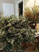 Faux ivy greenery with variegated leaves spreading outwards in container, placed on a counter.