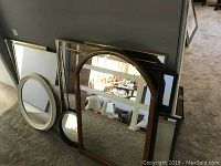 Group photo showing seven mirrors of varying shapes (rectangular, round, arched) and frame colors stacked against a wall.
