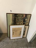 Four framed art pieces resting on carpet against wall showing size and framing styles.