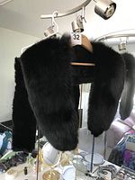 Black mink fur shawl hanging on a hanger, showing front and side views with thick fur and structured shape.