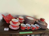 Full view of the red tea set including teapot, cups, saucers, and stacking dishes showing the overall quantity and colors of the lot.