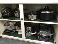 Wide view of assortment of cookware showing various pots and pans organized on shelves.