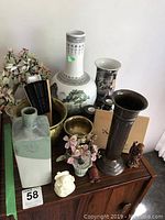 Wide view of assortment including vases, figurines, and faux flowers on wooden table