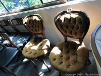 Two brown tufted chairs placed side by side near a window with sunlight casting shadows.